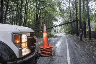 Image of a utility truck blocking access to a road with a downed power line.