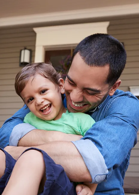 A smiling father and son on a porch.
